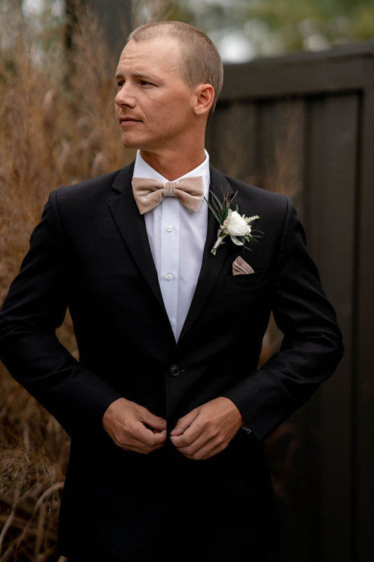 Groom, Getting Ready, Buttoning Suit, Black Tux, White Undershirt, Blush Bow Tie, Blush Pocket square, White Rose Boutonniere, Outdoor Venue, Wedding Day Photography, Knot Too Shabby Events, Wilmington Wedding Planner, NC Wedding Planner, The Barn at 
Rock Creek, 