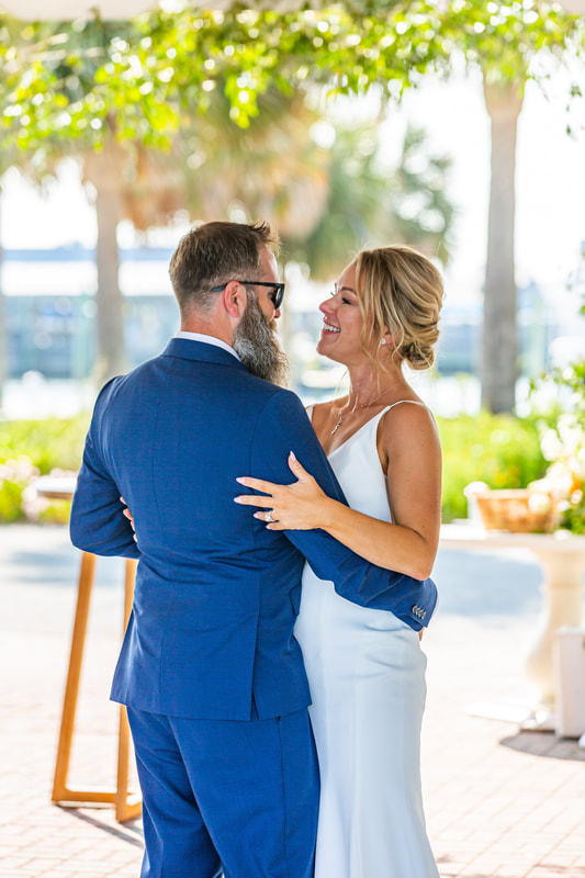 Knot Too Shabby Events, NC Wedding Planner, NC Wedding Coordinator, Bald Head Island Wedding, Summer Wedding, Pink, Blue, White, Coastal Chic, Elegant, Coral, Teal, Bride and Groom slow dancing in a blue tux and white dress under a tent outside. Ocean and palm trees in the background. 