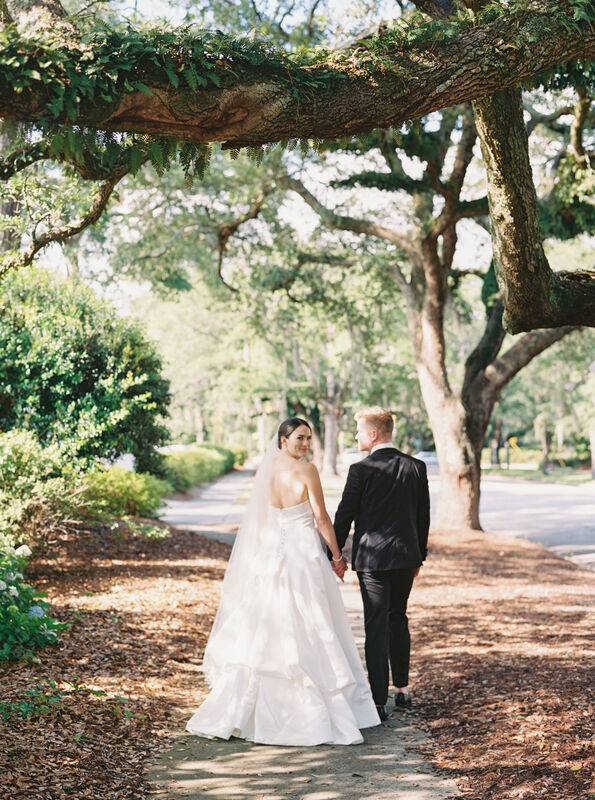 Bride and Groom, Walking Outside, Oak Tree Framed Sidewalk, Outdoor Photography, Couples Photos, Wedding Day Photography, White Strapless Wedding Dress, Looking Back at Camera, Black Tux, Cape Fear Country Club, Knot Too Shabby Events, Wilmington Wedding Planner, NC Wedding Planer, 