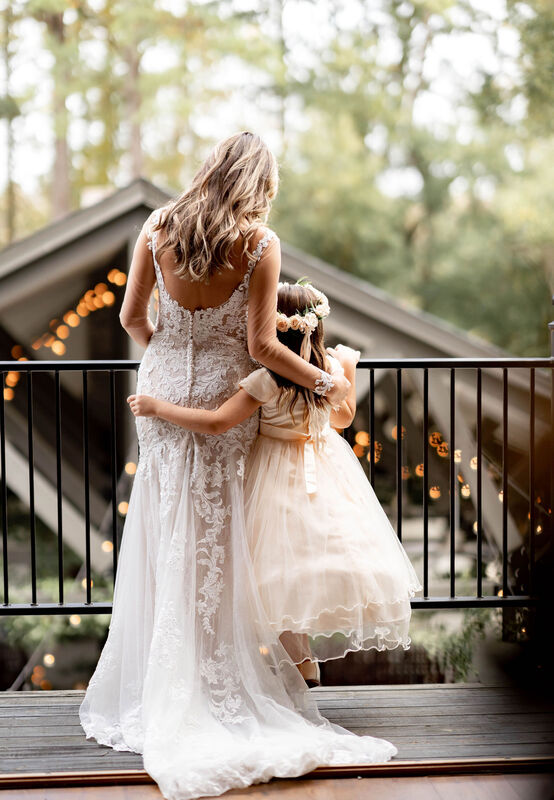 Bride, Flower Girl, Venue Balcony, Edison Lights, Stepmom and Daughter Hugging, Flower Girl Dress, Flower Crown, Wedding Dress, White Dress, Lace Dress, Wedding Day Photography, Outdoor Venue, The Barn at Rock Creek, Knot Too Shabby Events, Wilmington Wedding Planner, NC Wedding Planner, 