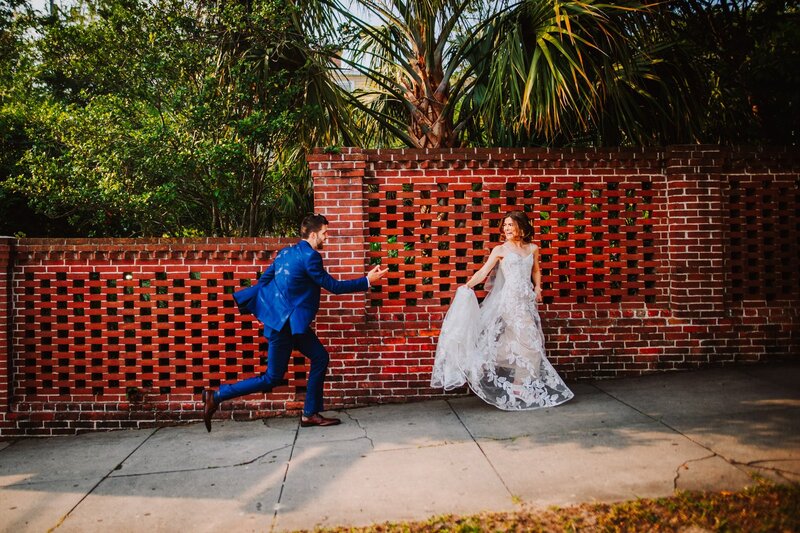 Bride and Groom, Wedding Day Photos, Groom Chasing Bride, Sidewalk, Detailed Brick Background, White Dress, Wedding Dress, Blue Tux, Unique Wedding Photography, Just Married, Happy Couple, Knot Too Shabby Events, Wilmington Wedding Planner, North Carolina Wedding Planner, 