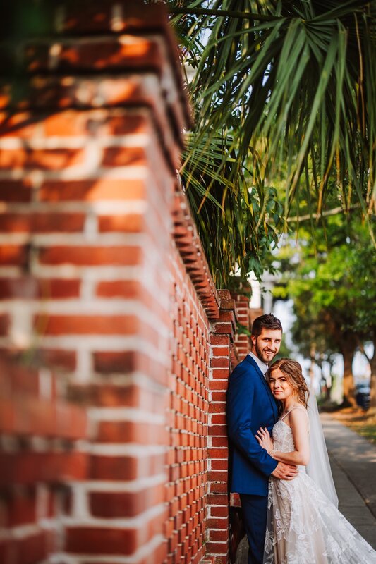 Bride and Groom, Couple Photo, Husband and Wife, Detailed Brick Side Wall, White Dress, Wedding Dress, Blue Suit, Blue Tux, Wedding Day Photography, Outdoor Photos, Using Surrounding Areas as Background, Knot Too Shabby Events, Wilmington Wedding Planner, North Carolina Wedding Planner, 