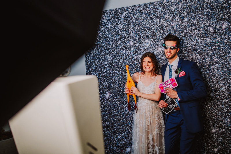 Bride and Groom, Photo Booth, Glitter Background, White Dress, 
Wedding Dress, Blue Suit, Blue Tux, Photo Booth Props, Chicken, Sunglasses, Wedding Vendor, Knot Too Shabby Events, Wilmington Wedding Planner, North Carolina Wedding Planner, 